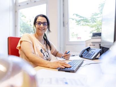 Glückliche Frau sitzt im Büro am Schreibtisch