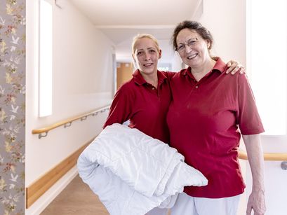 Zwei Mitarbeiterinnen mit Bettwäsche auf dem Flur