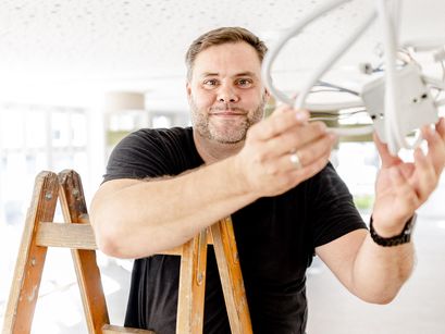 Mann auf Leiter repariert Kabel
