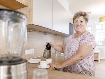 Bewohnerin gießt sich Kaffee in der Küche ein