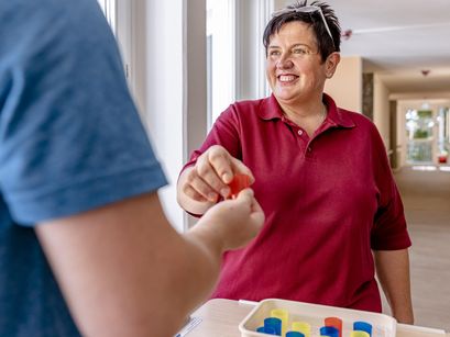 Pflegekraft gibt einem Bewohner einen kleinen Becher Medizin