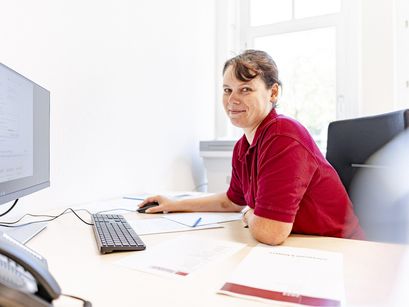 Pflegerin sitzt im Büro am Schreibtisch